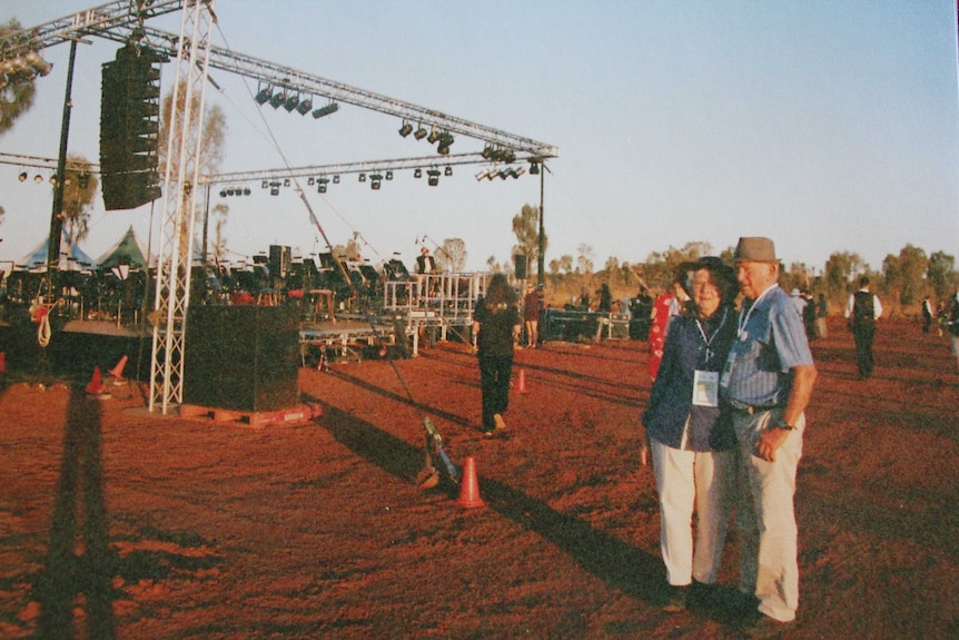 Elvie and Norm Lambert standing near DSO stage set up in red dirt in Northern Territory.