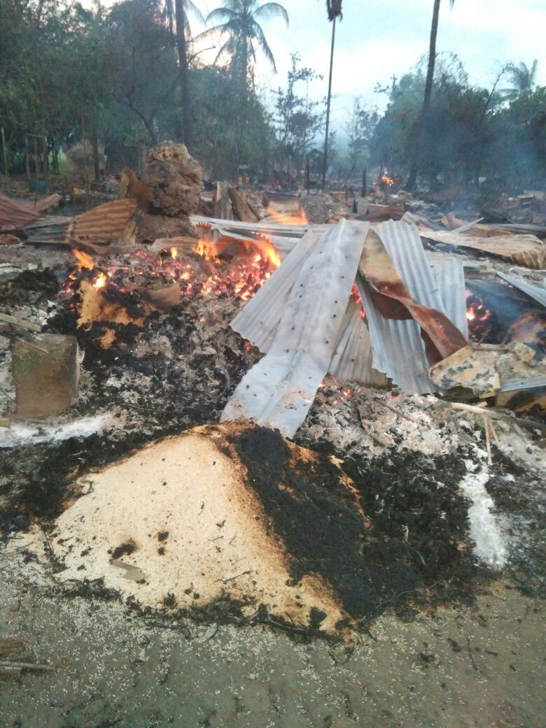 Twisted sheets of corrugated iron and burning wood and mud in a Rohingya village.