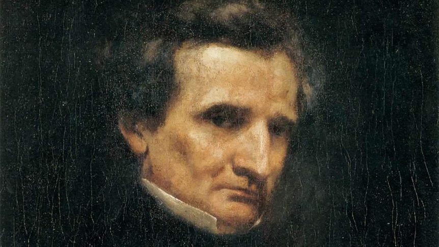A dark and crackled old portrait of Hector Berlioz, looking very stern.