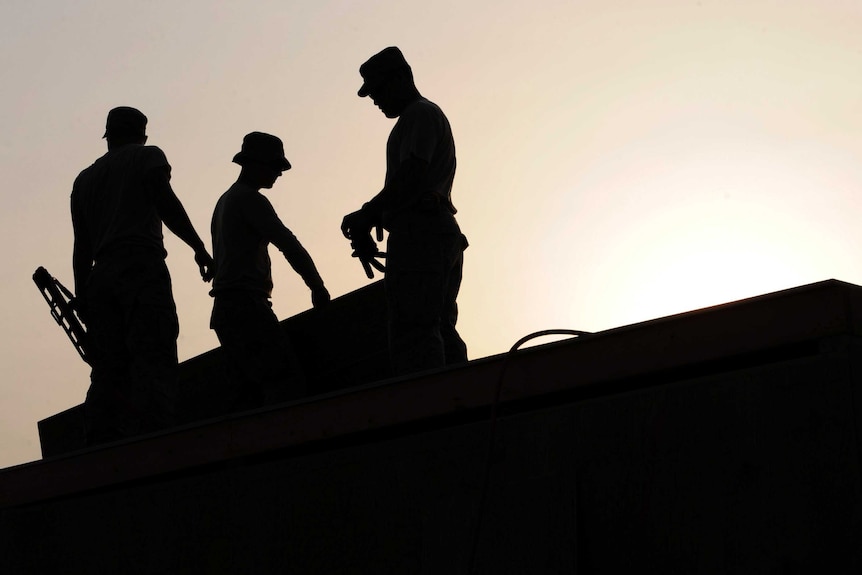 Silhouette of construction workers on roof