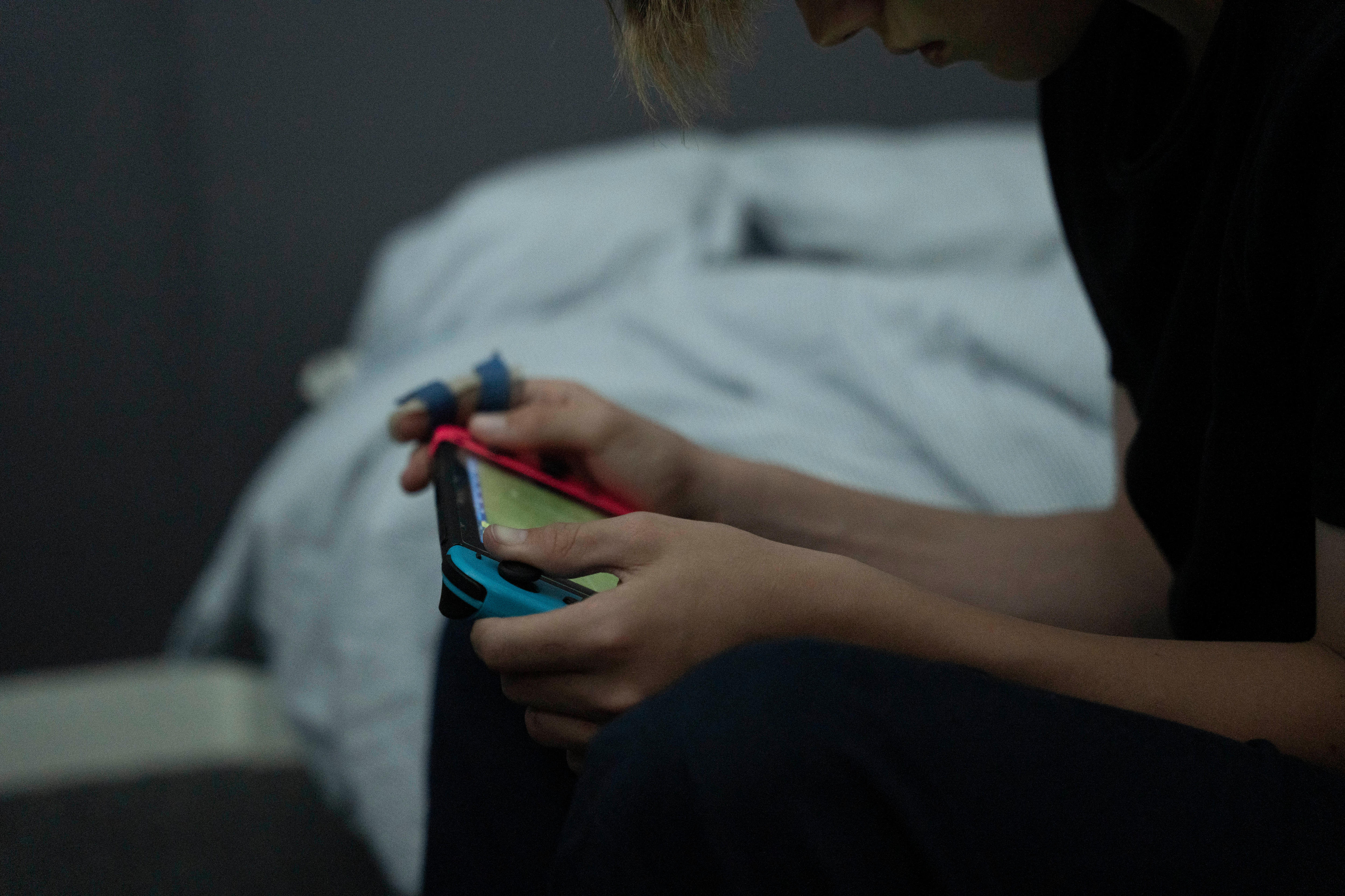 Side on view of unidentified youth playing a Nintendo Switch
