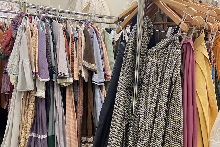 Many colored dresses are tightly hung on the shelves