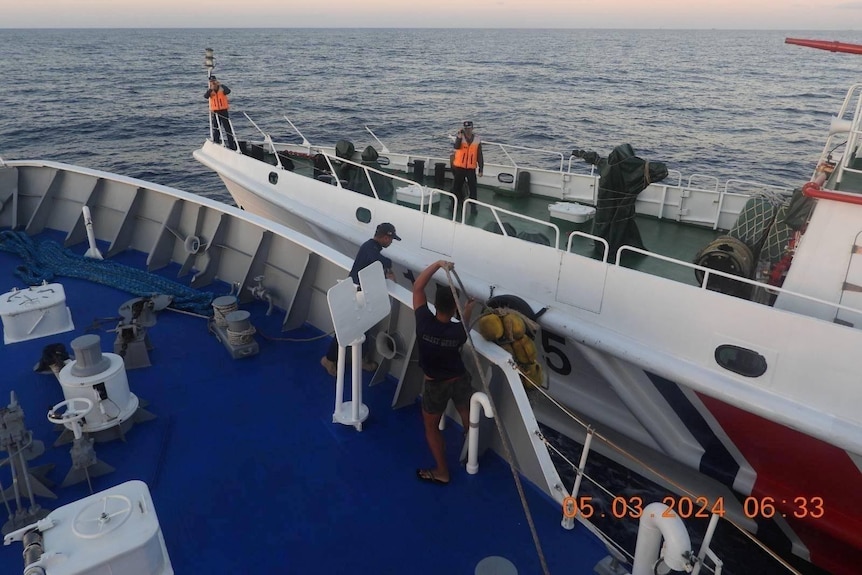 Philippine Coast Guard personnel try to prevent damage by putting soft fenders between their vessel and the Chinese ship.