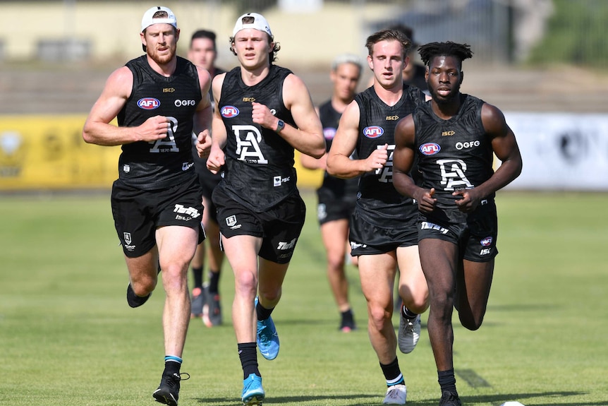 AFL footballers are seen running laps at training in Adelaide.