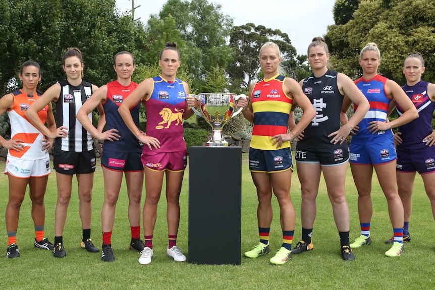 Captains of the 10 AFLW teams pose with the premiership cup