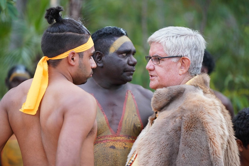 Ken Wyatt wearing his kangaroo skin cloak, speaks intently with Michael Yunupingu.