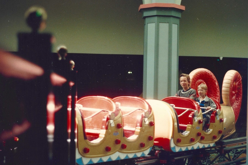Two young boys on the back of the dragon coaster in Top's
