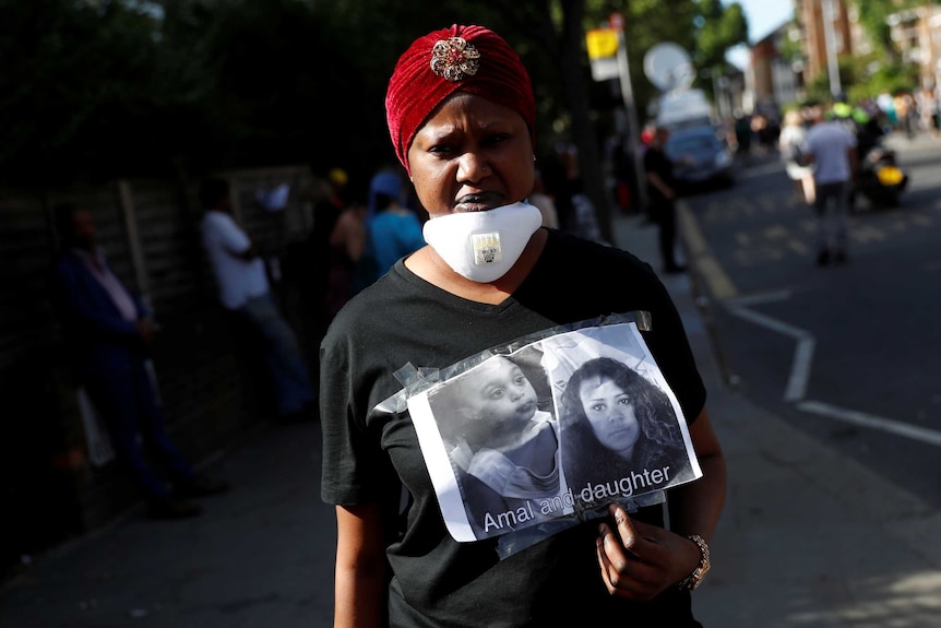 A woman holds a missing person posters near the Grenfell Tower block.