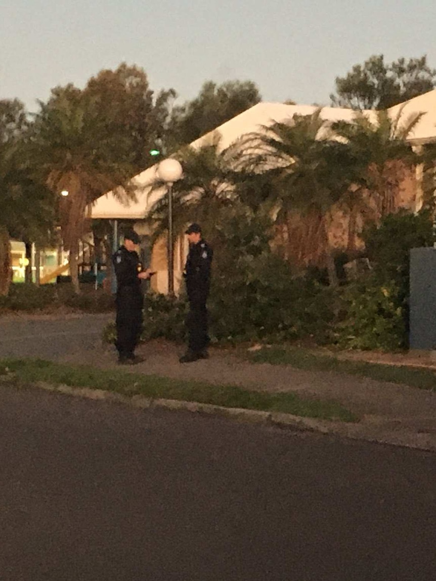 Two policemen standing outside a brick building near a police car.