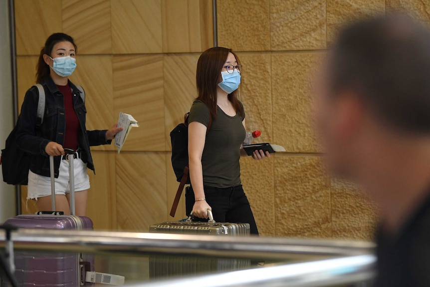 Women in masks arrive with bags
