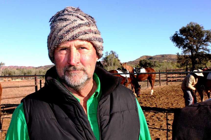 A close up profile picture of Shane Muldoon. Horse yards and a mountain range are in the background.