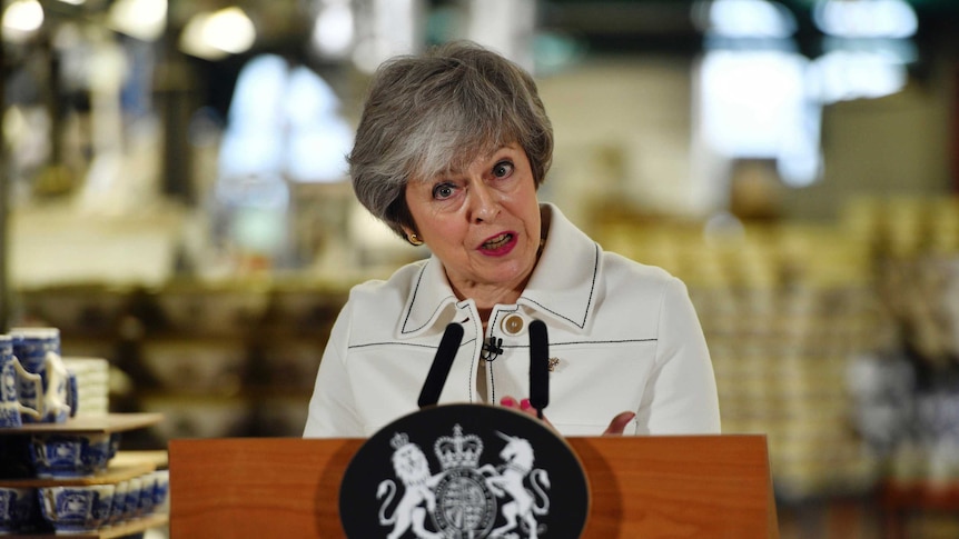 Britain's Prime Minister Theresa May pulls a face as she speaks in front of a podium.