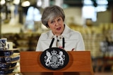Britain's Prime Minister Theresa May pulls a face as she speaks in front of a podium.