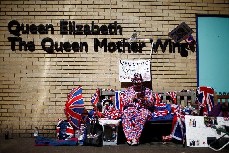 A fan of Britain's royal family sits in the sun outside St Mary's Hospital