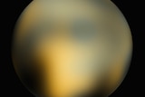 This image of Pluto  by the Hubble Space Telescope shows it as a yellow ball with no clear features against a black background.