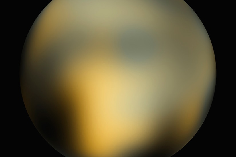 This image of Pluto  by the Hubble Space Telescope shows it as a yellow ball with no clear features against a black background.