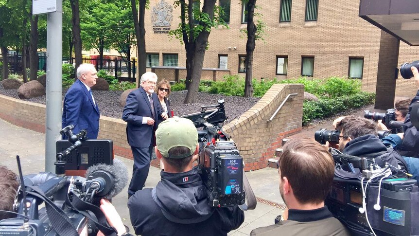 Rolf Harris walks towards court with his niece, past cameramen.