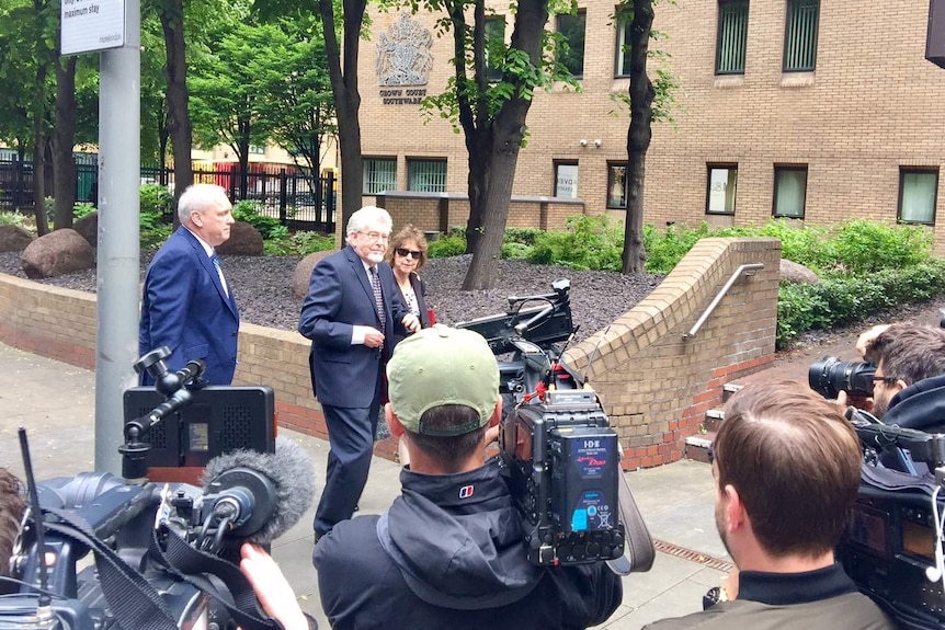 Rolf Harris walks towards court with his niece, past cameramen.