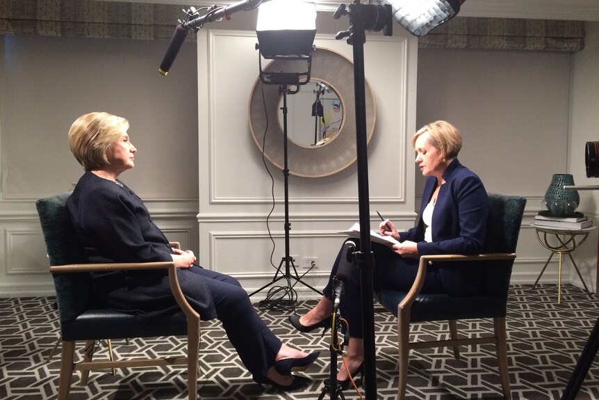 Side shot of Ferguson and Clinton facing each other during interview with lights and microphones around them.