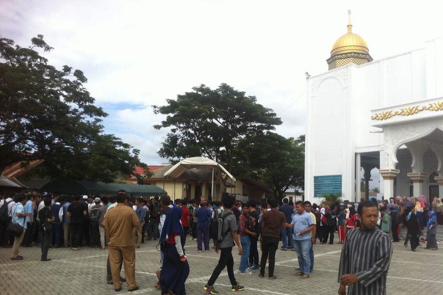 A crowd gathers in font of a marquee at a mosque where two gay men are set to be flogged in Aceh.