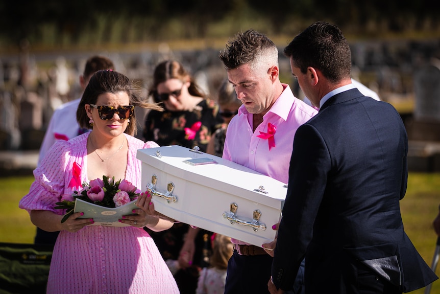 Grieving parents carry small coffin.