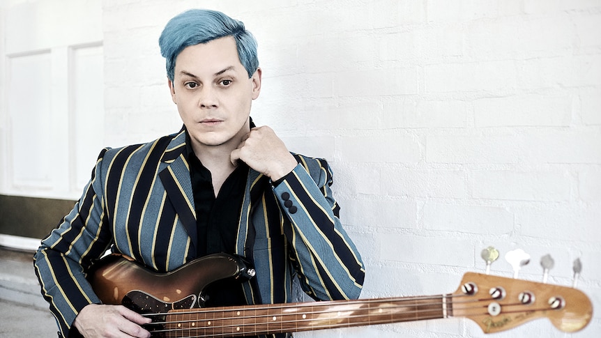 Jack White has blue hair, wears a striped jacket, holds a bass guitar