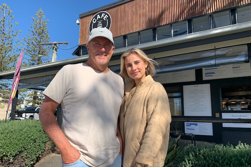 Owner and his daughter smiling standing outside the front of cafe 