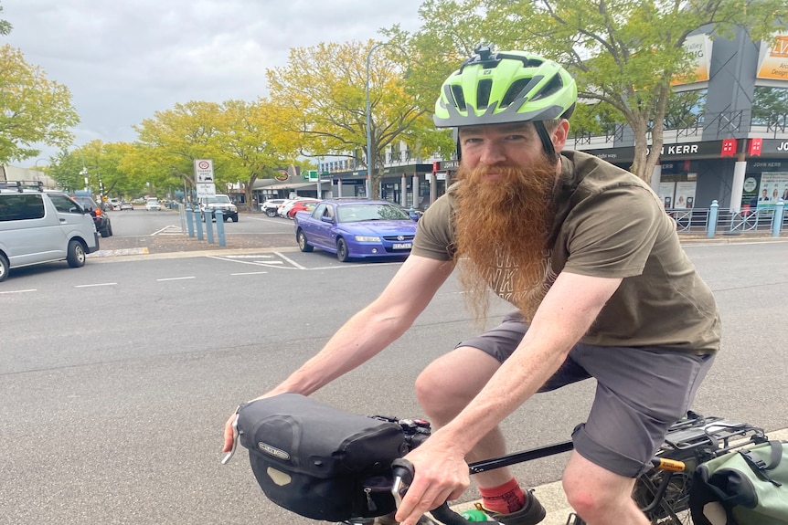 Man with a long ginger beard sitting on a bike wearing a helmet.