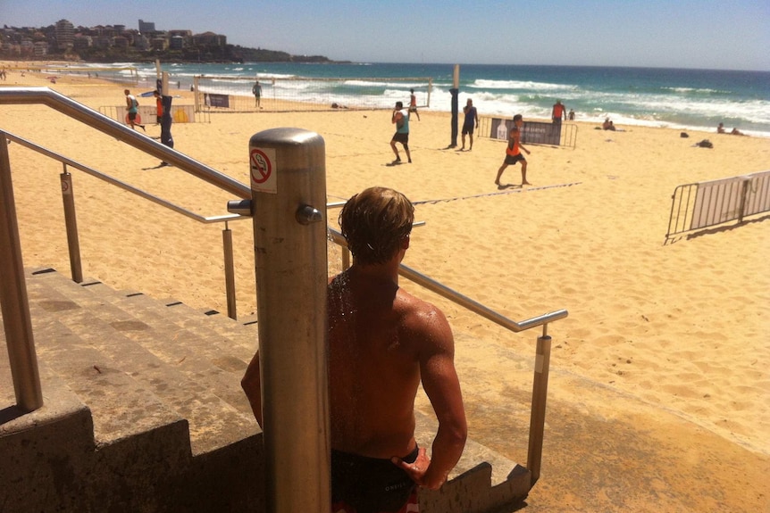 A volleyball player takes a shower to cool down at Manly Beach.