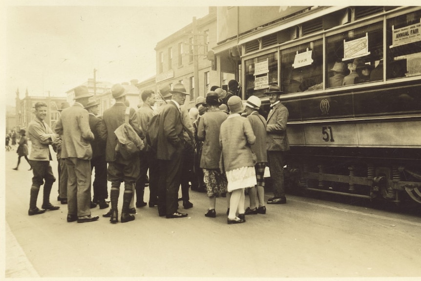 An old image shows people lining up to board a tram in Hobart.