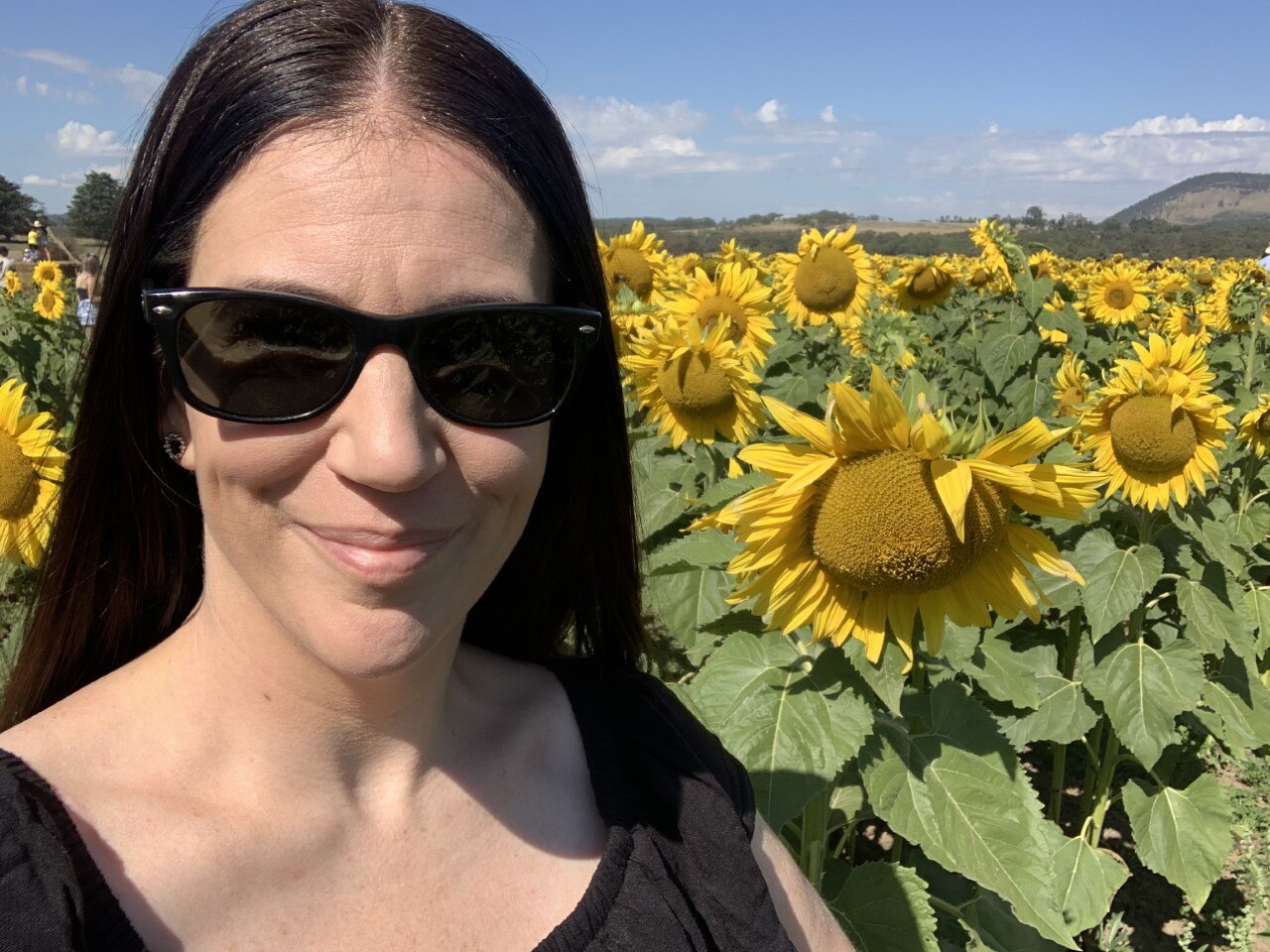 Woman smiles in field of sunflowers