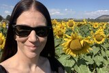 Woman smiles in field of sunflowers