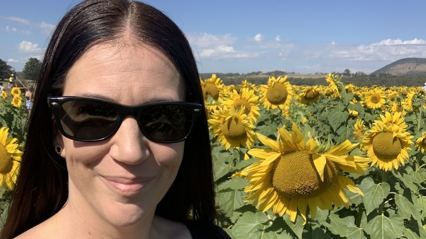Woman smiles in field of sunflowers