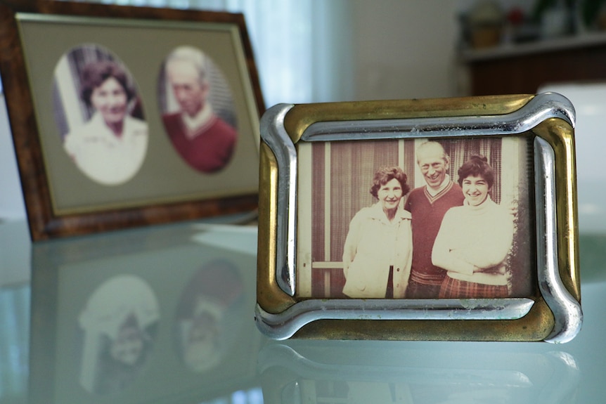 A framed photo of a young woman standing in front of an older man and woman.