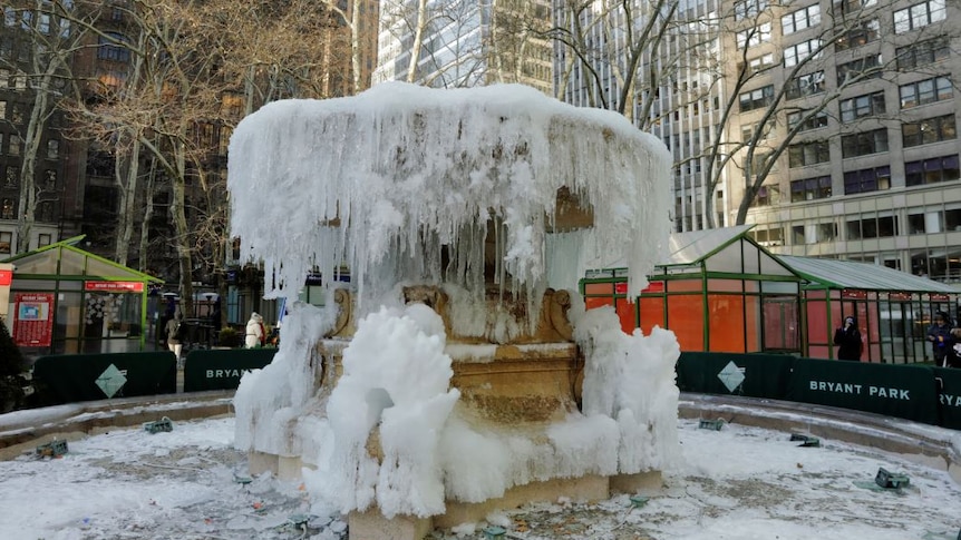 Pedestrians stop to look at the frozen Josephine Shaw Lowell Memorial Fountain.