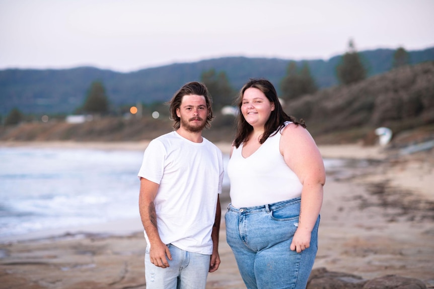 image of man in white shirt jeans and woman in white shirt and jeans on beach