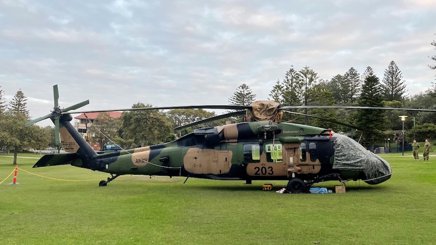 A Black Hawk helicopter in a green lush park during the day.