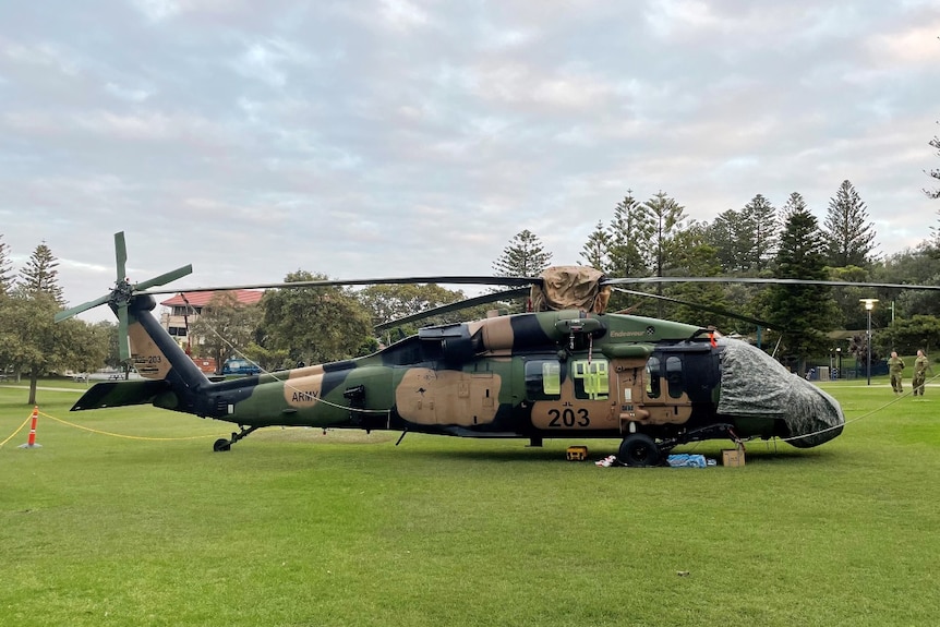A black hawk helicopter in a green lush park during the day