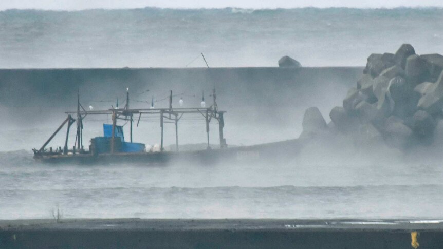 small fishing boat in sea mist near rocks