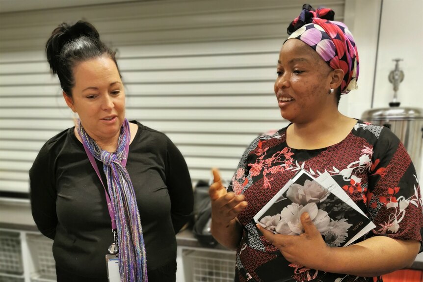 Two women stand together talking