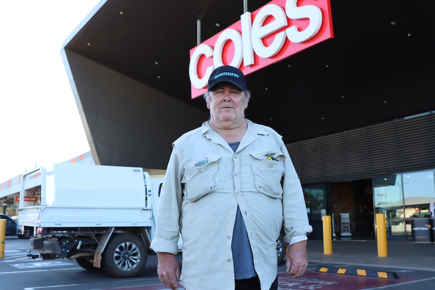 He stands in a cap outside Coles
