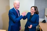 Joe Biden and Kamala Harris laughing and clasping hands