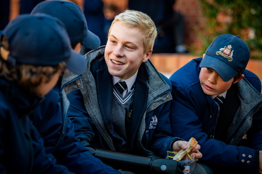 Knox surrounded by friends at school, smiling as he talks.