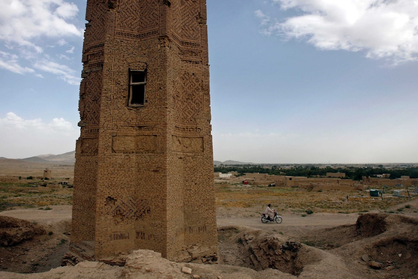 A motorcyclist rides past one of the minarets in the city of Ghazni August 6, 2007.