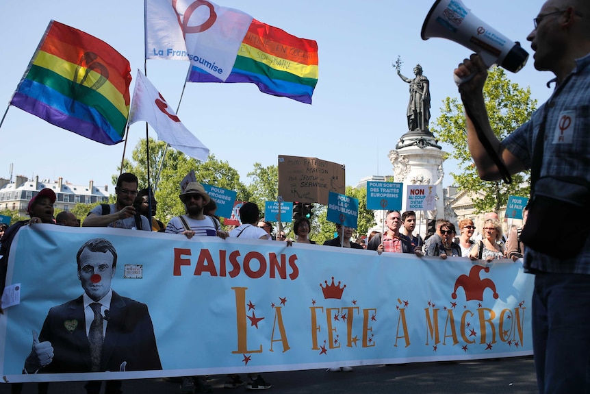 Protesters carry a banner reading: "Let's celebrate Macron" as they rally in Paris, France, Saturday, May 5, 2018.