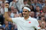 Roger Federer pumps his fist and smiles at the crowd at Wimbledon after winning his fourth round match.