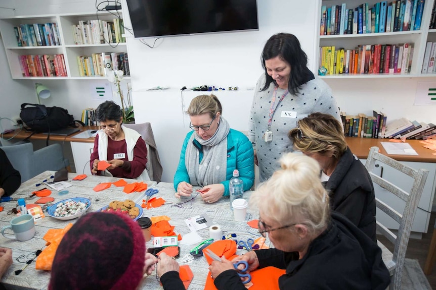 Women sit at a table and sew