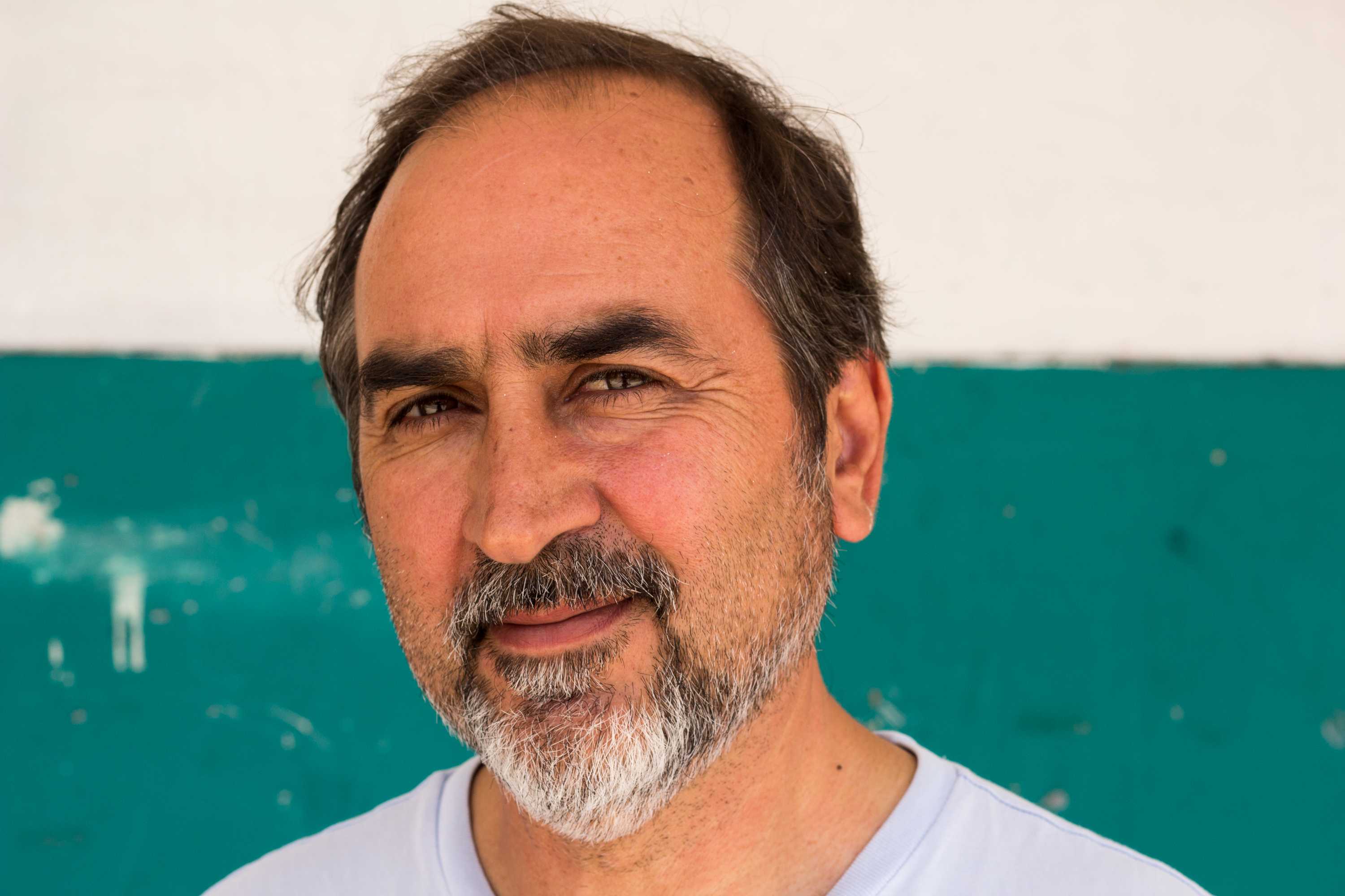Fereydoun Najafi Aria standing in front of teal and white wall in Sydney.
