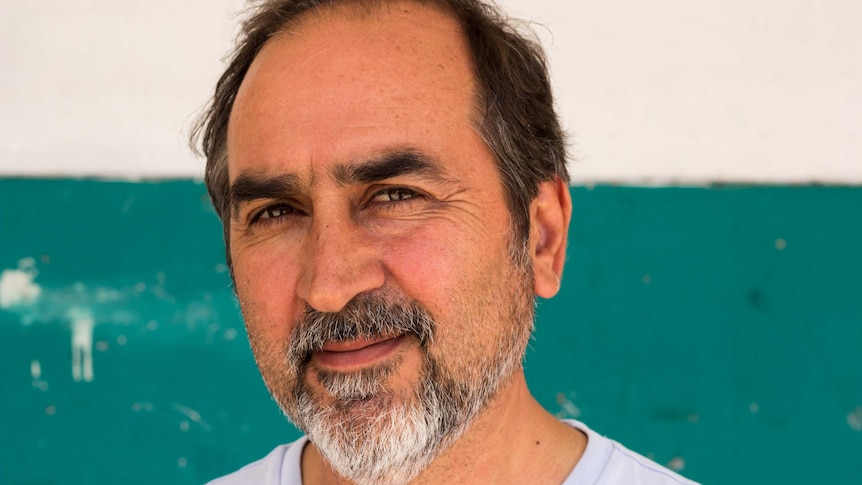 Fereydoun Najafi Aria standing in front of teal and white wall in Sydney.