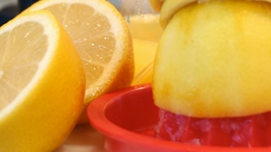 A number of lemons are cut in half and juiced.